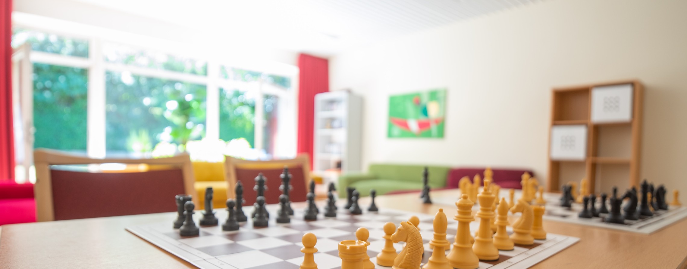 Das Bild zeigt einen Aufenthaltsbereich der LWL-Tagesklinik Herne mit einem Schachbrett im Vordergrund.
