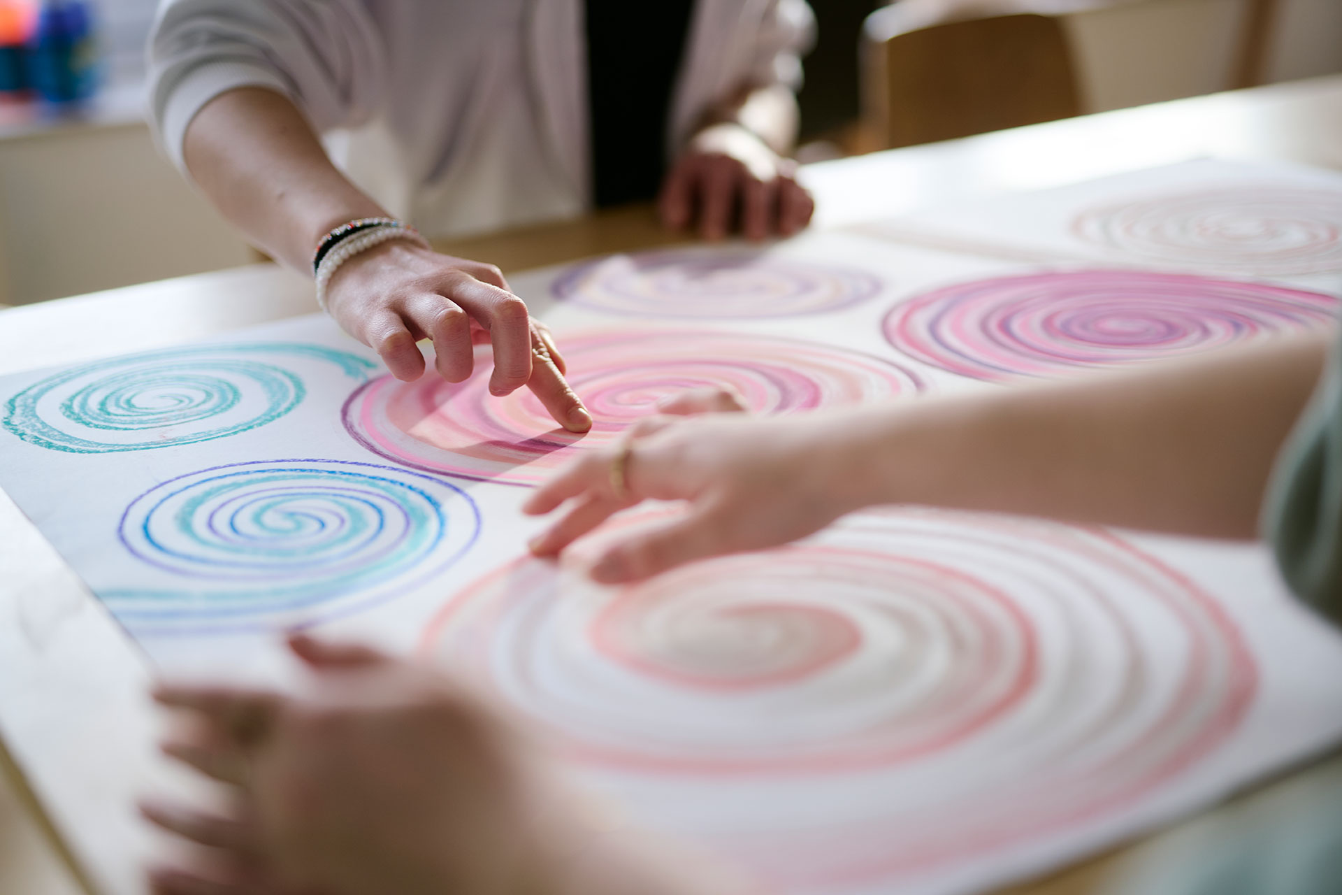 Zwei Personen gestalten ein Bild, sie malen bunte Kreisel.