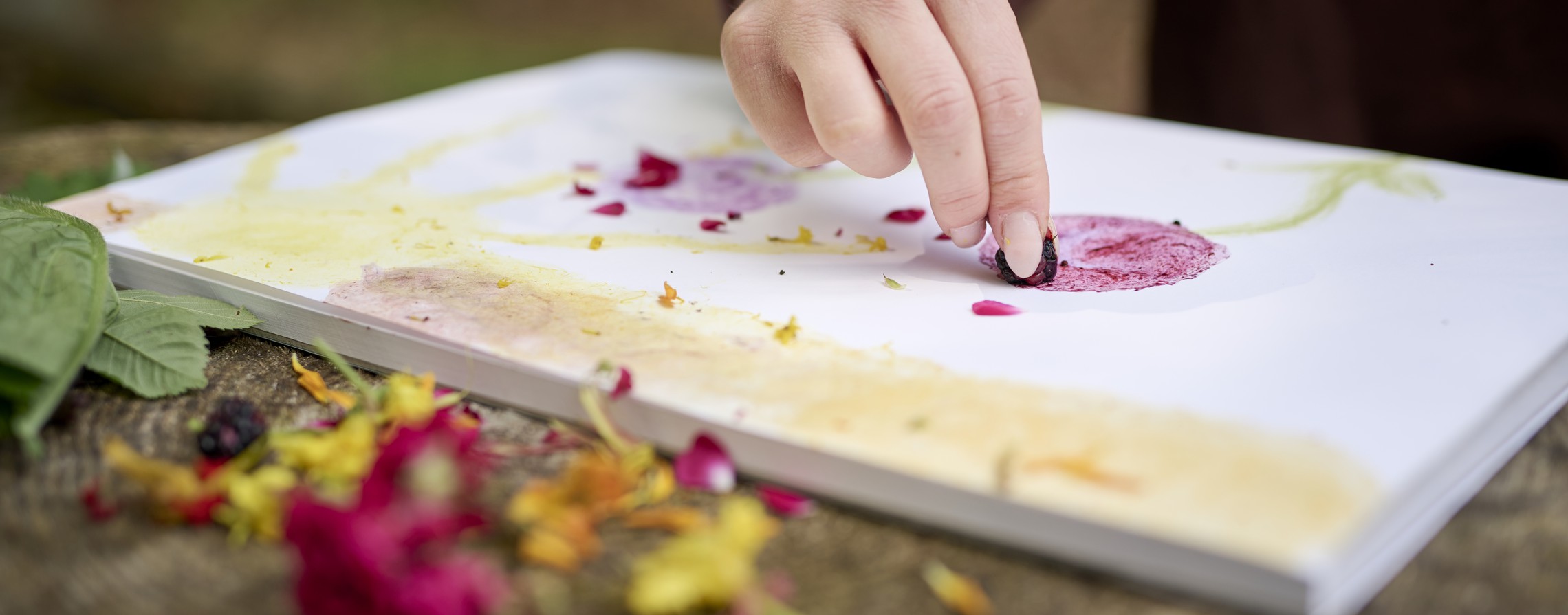 Eine Person malt ein Bild mit Waldmaterialien.