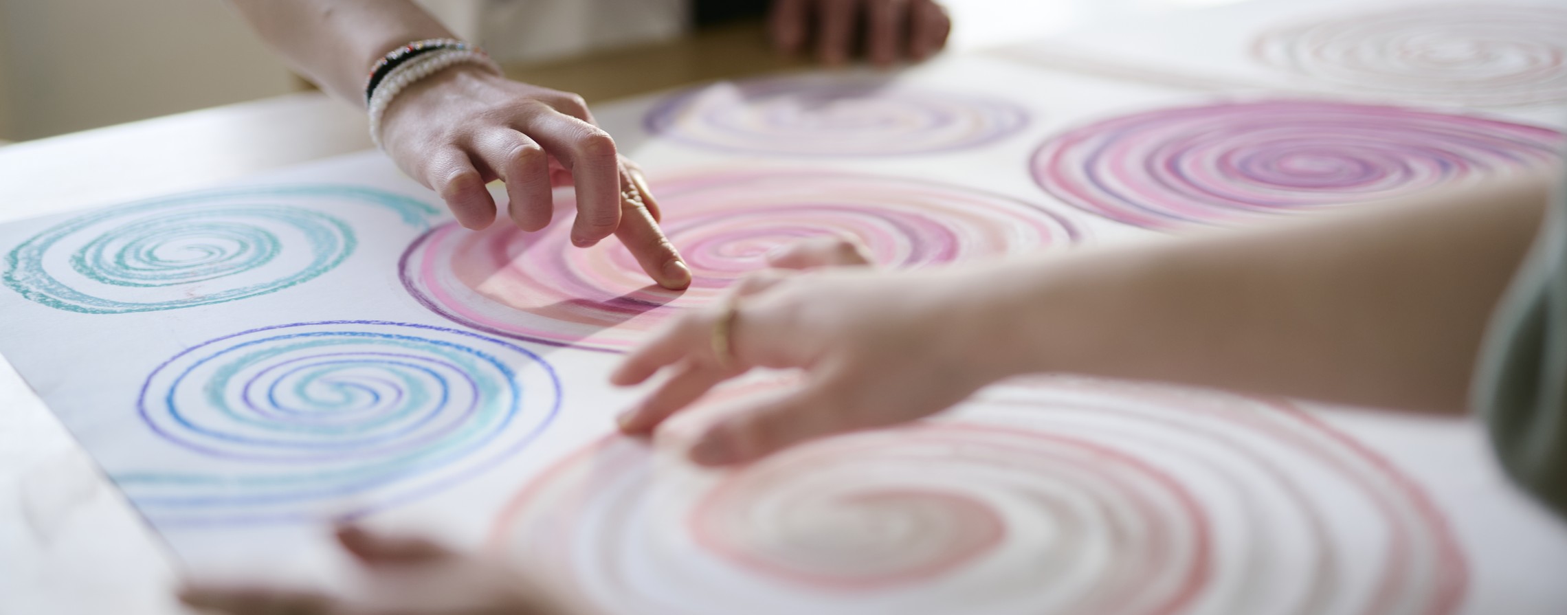 Zwei Personen gestalten ein Bild, sie malen bunte Kreisel.