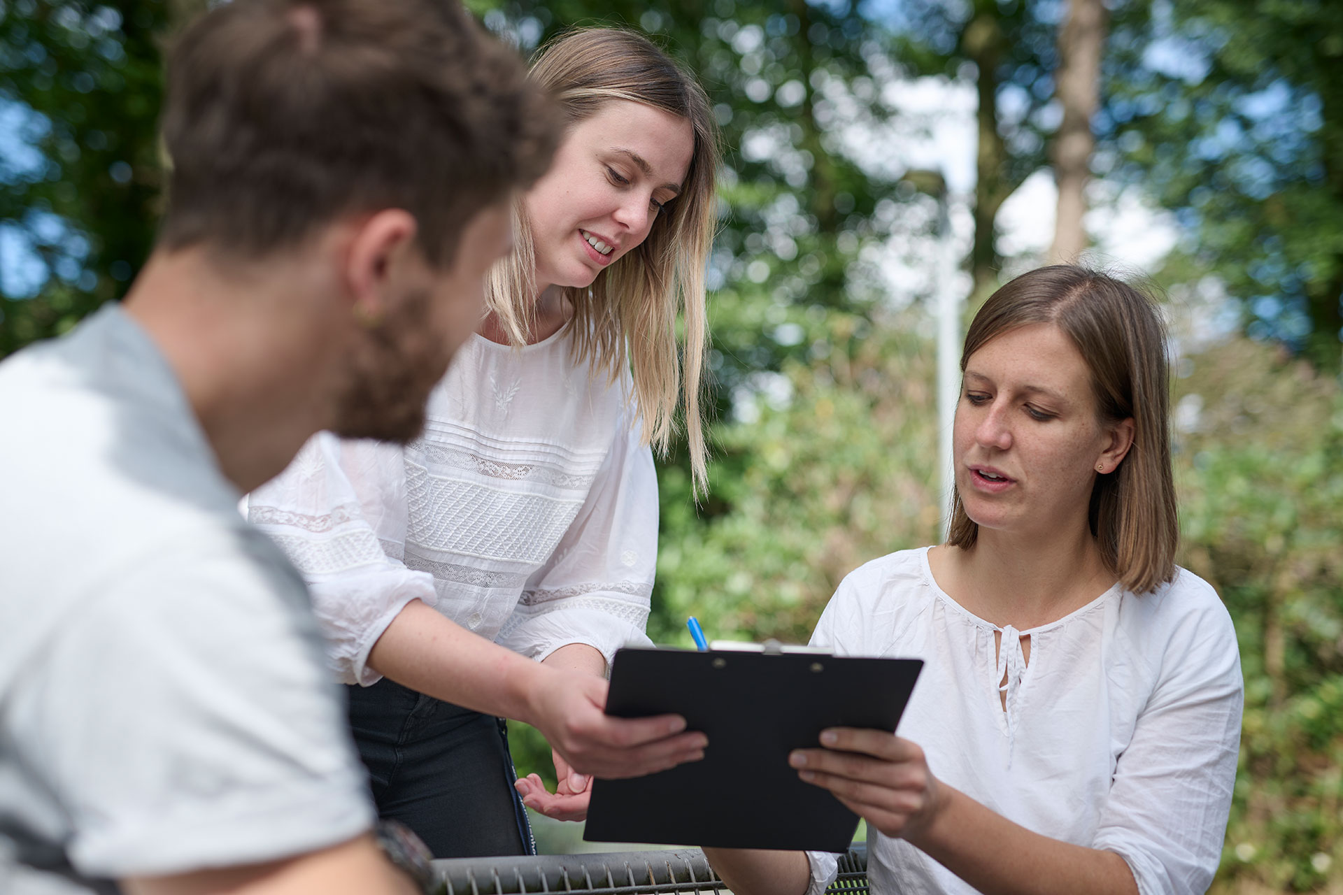 Das Bild zeigt drei Kolleg:innen, die auf ein Dokument schauen.