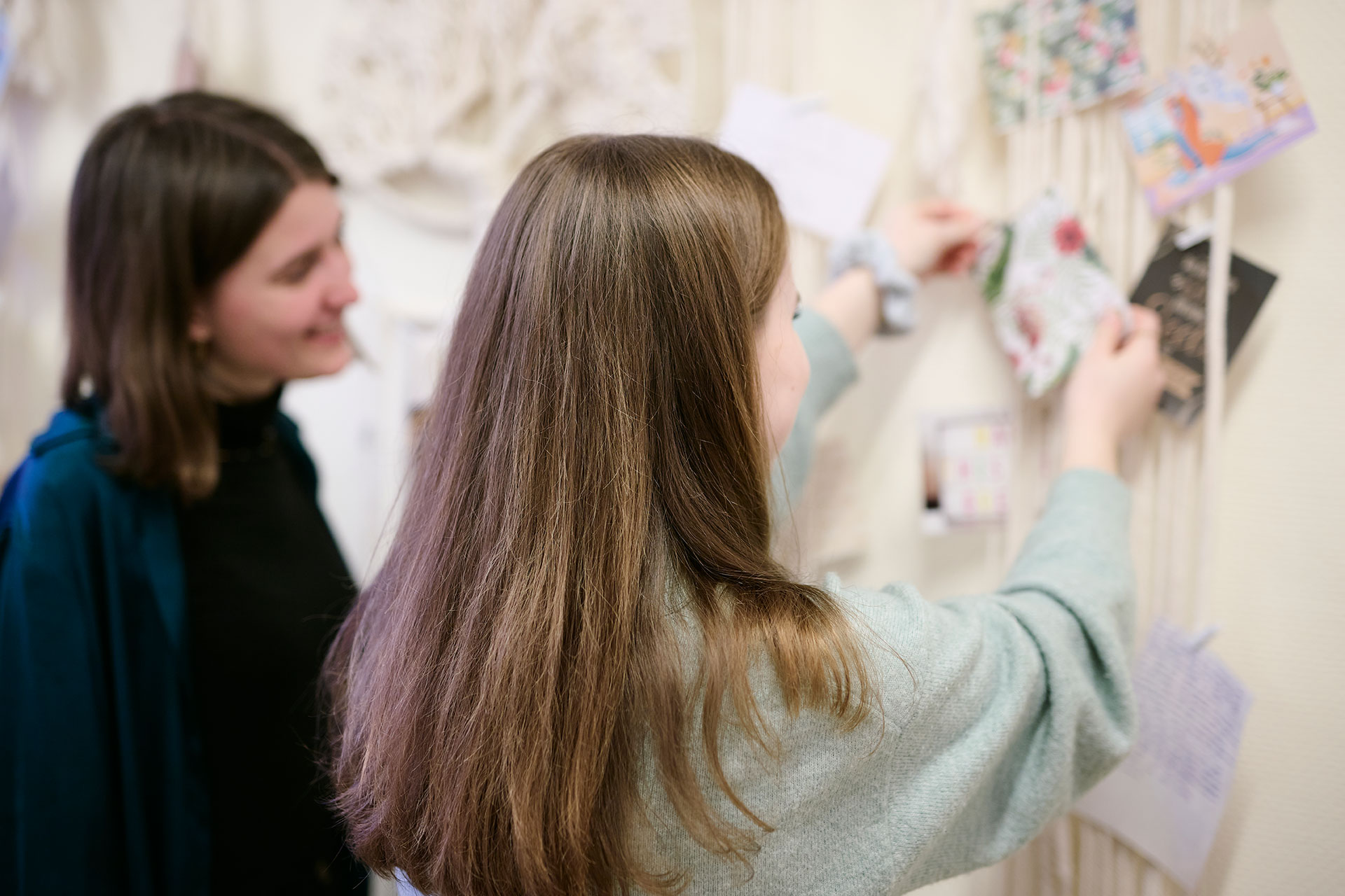 Eine Therapeutin und ein junges Mädchen pinnen eine Karte an eine Wand.