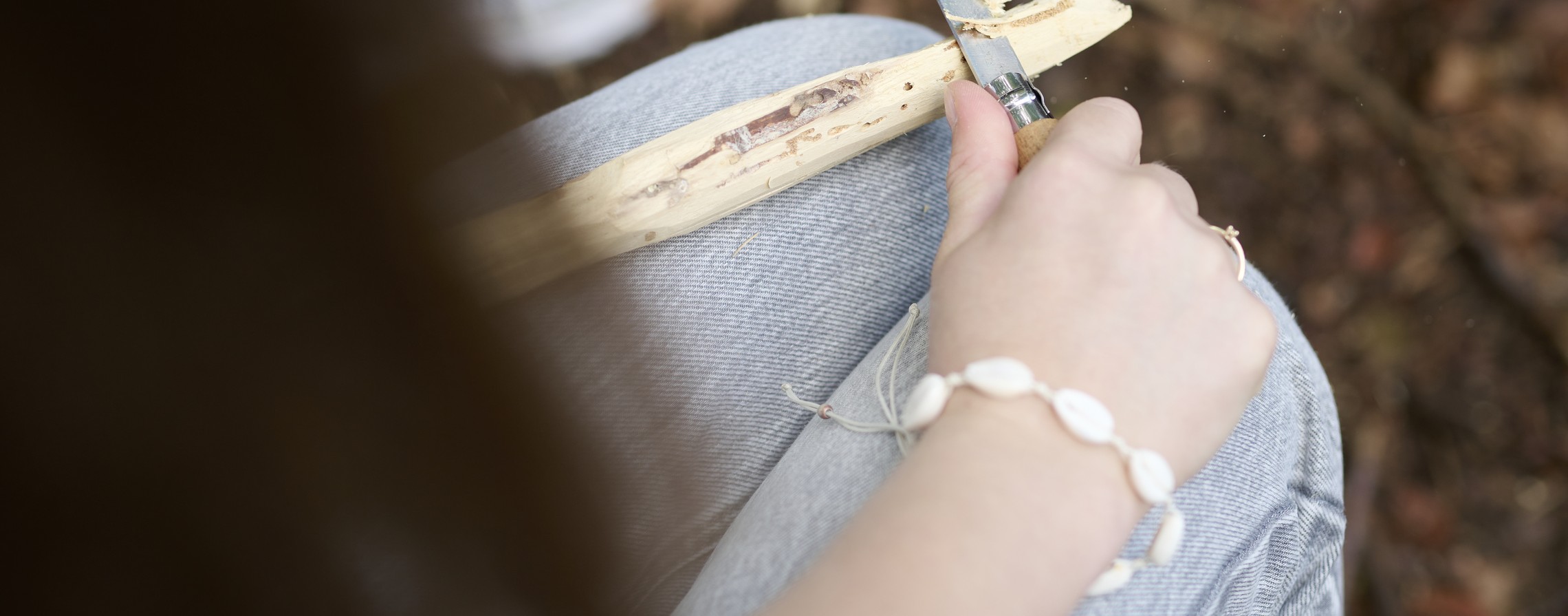 Ein Mädchen schnitzt etwas im Rahmen der Waldpädagogik.