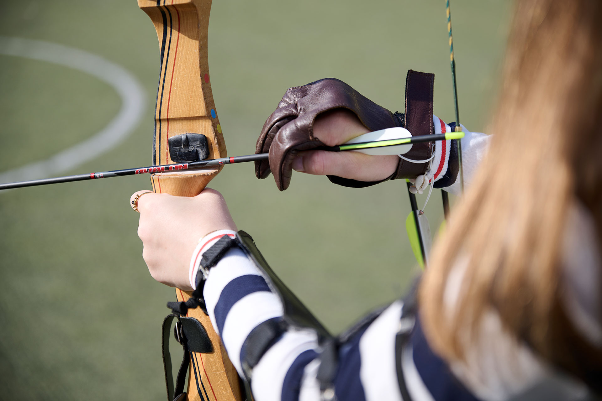 Eine Person spannt im Rahmen des Therapeutischen Bogenschießens einen Bogen auf.