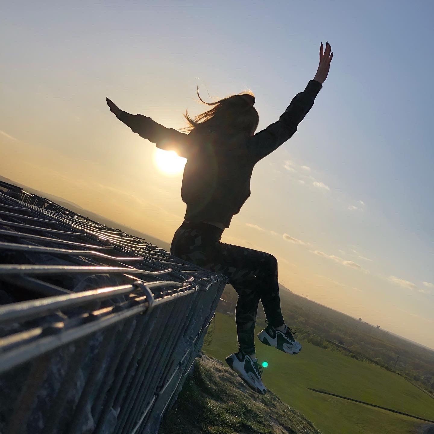 Das Bild zeigt ein Mädchen, das sich einen Sonnenuntergang anschaut.