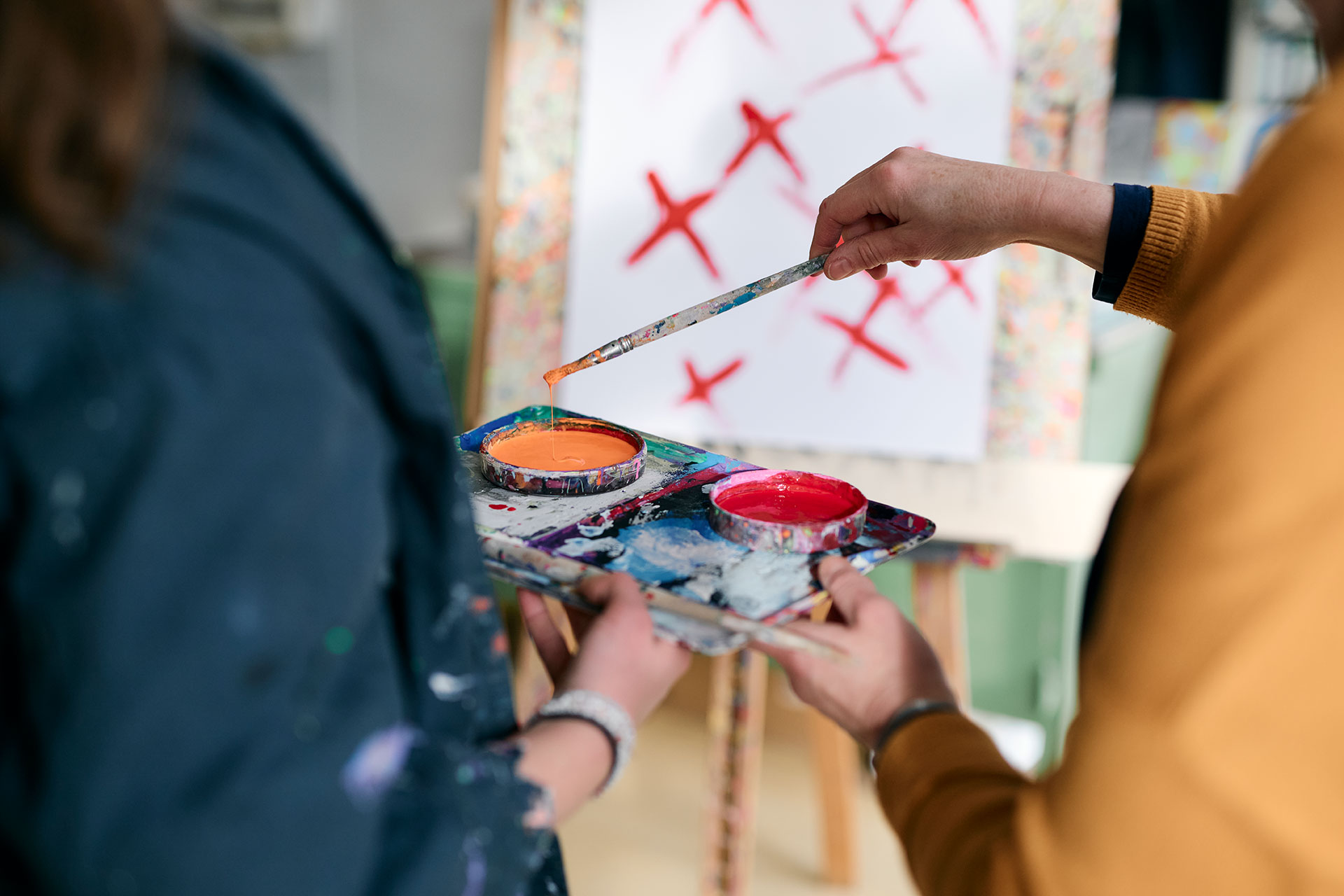 In der Kunsttherapie malt eine Patientin ein Bild und bekommt dabei Unterstützung von einer Kunsttherapeutin.