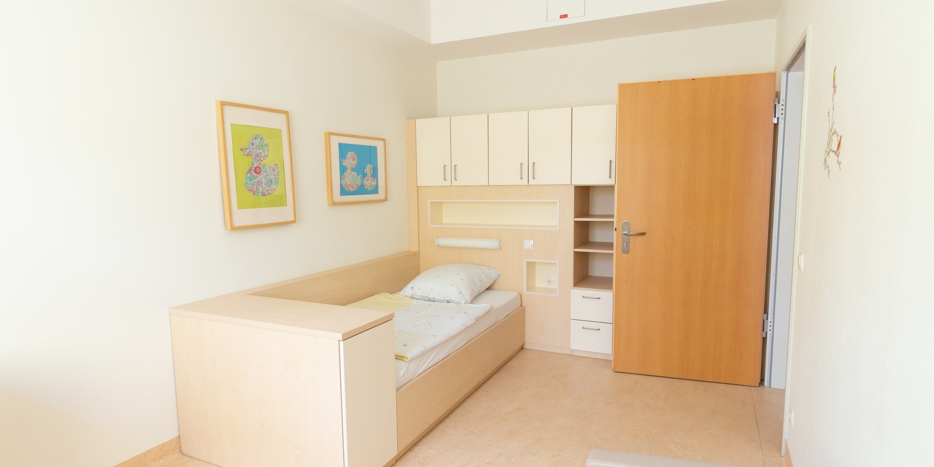 Das Bild zeigt ein Patientenzimmer mit einem Bett und einem Schrank.