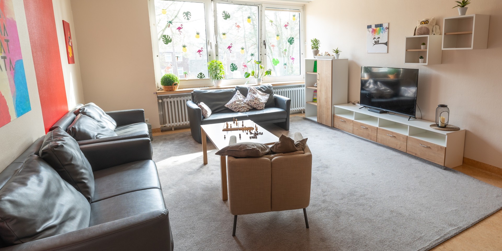 Das Bild zeigt einen Freizeitraum mit einem Sofa und einem Fernseher.