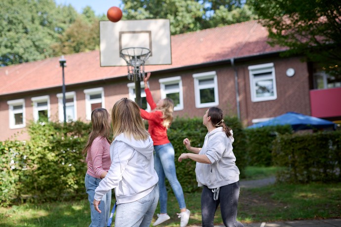 Mehrere Personen spielen draußen Basketball.