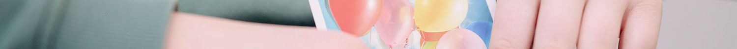 Das Bild zeigt ein Kind, das eine Gefühlskarte mit Luftballons hält.