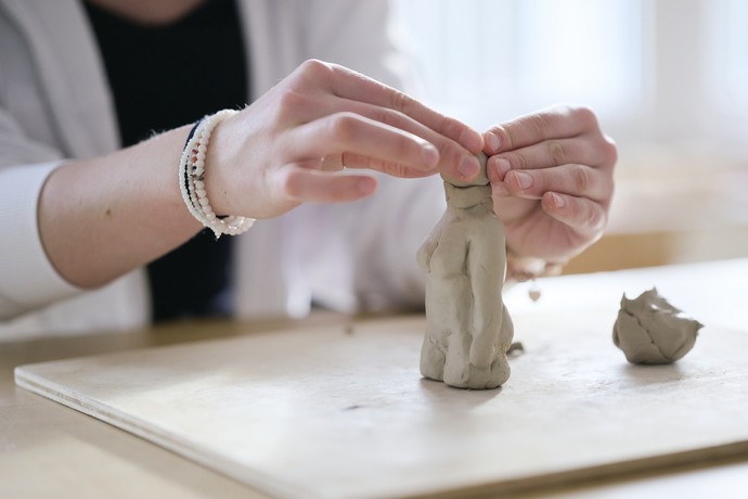 Eine Person modelliert eine Figur aus Ton.