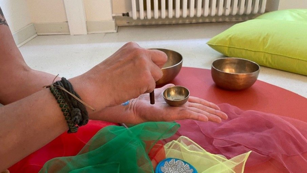 Auf dem Bild ist eine Hand zu sehen, die eine Klangschale hält.