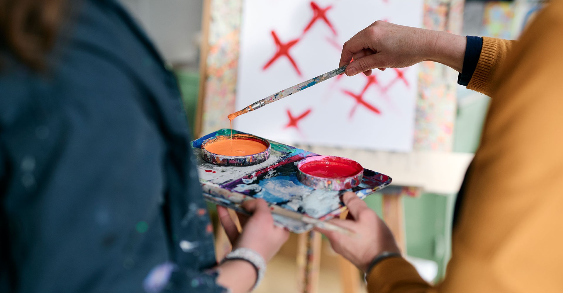 In der Kunsttherapie malt eine Patientin ein Bild und bekommt dabei Unterstützung von einer Kunsttherapeutin.
